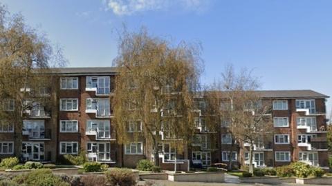 Four-storey brick block of flats with trees in front