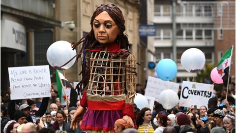Little Amal, the 3.5 metre-tall puppet representing a migrant Syrian girl, stopped through Coventry while on her 8,000km journey across Europe. Little Amal joined The Walk, as part of Coventry City of Culture 2021 events.