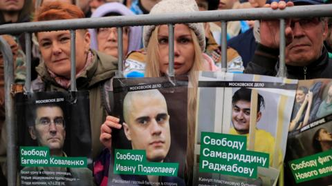 Demonstrators in Moscow hold up posters showing the faces of jailed protesters on Sunday 29 September