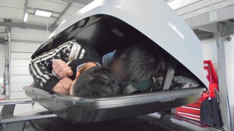 The three people lying inside the roof box