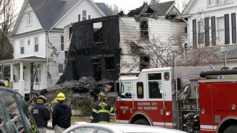 Fire officials stand at the scene of an early morning house fire in Baltimore on January 12, 2017.