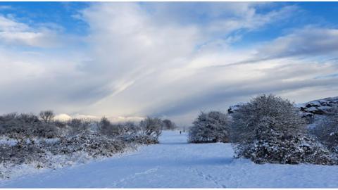 A snowy fields under a sky of broken cloud