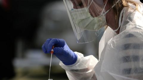 Physician Aliea Herbert places a swab into a tube after administering a test for coronavirus disease to a patient in Seattle, Washington, US, 29 April 2020