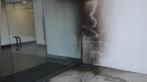 The building entrance shows fire damage