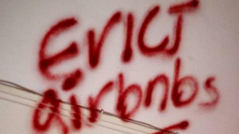 The words "evict Airbnbs" spray-painted on a wall.