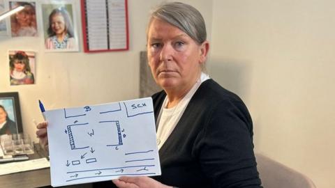 Sharon holds a whiteboard with a map of the Wear Garth flats drawn on