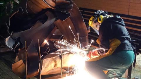 Artist Sarah Tombs works on the sculpture