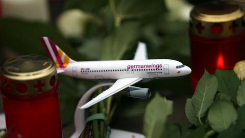 A toy airplane of German airline Germanwings is placed between candles and flowers