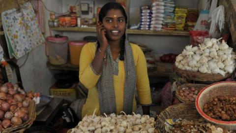 An Indian woman talks on her mobile phone at a vegetable market in Hyderabad