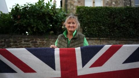 woman standing behind Union flag