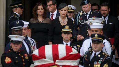 Cindy McCain holds hands with her son James as they follow her late husband John McCain's casket and a military honour guard