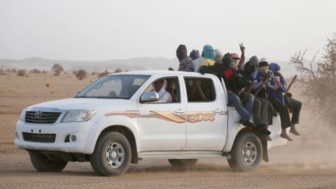 Migrants crossing the Sahara desert into Libya ride on the back of a pickup truck outside Agadez, Niger, May 2016