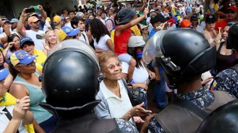 A woman talks to a line of Bolivarian National Police officers, PNB, during a protest against Nicolas Maduro in Caracas