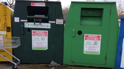 A picture of a dark green and a light green recycling bin with stickers on bearing the name: Helping Our Future.