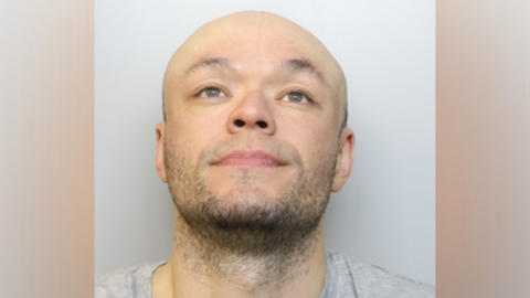 Jamie Doyle custody image. He is wearing a grey T-shirt and is looking up into the air.