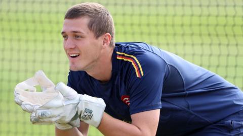 Simon Fernandes, wearing wicketkeeper gloves, prepares to take a catch during a training session