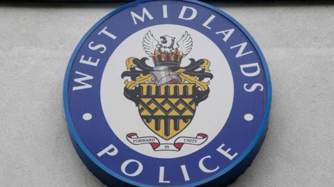 A West Midlands Police circular logo outside LLoyd House, the police HQ in Birmingham. It has a blue rim with West Midlands Police written in white and a phoenix risding from flames, Forward in Unity, it says