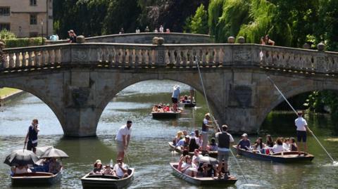 Punters in River Cam, with a bridge in the background