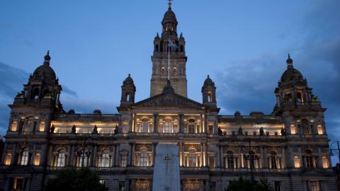 Glasgow City Chambers lit up at night overlooking the city's George Square