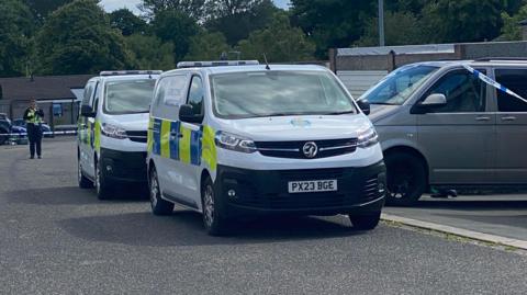 Police cars at the scene at Whernside in Carlisle, with an officer in the distance