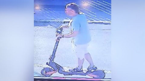 CCTV image of man on black and orange scooter