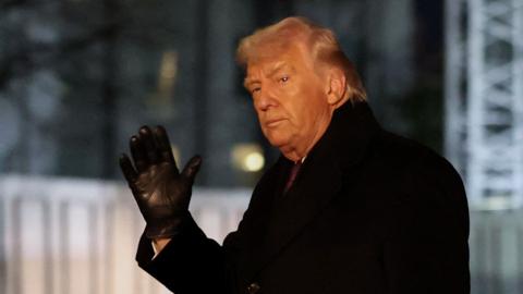 Donald Trump in a black coat waving