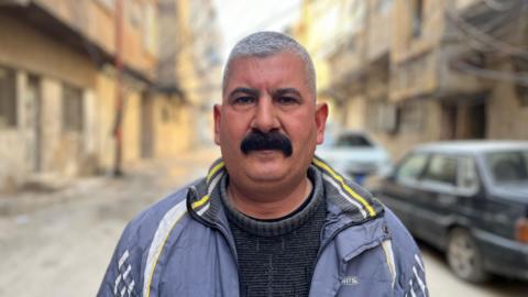 Tawfiq Diam, staring at a camera, in the middle of a street