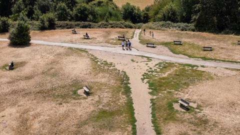 An aerial view shows the dirt paths and scorched grass of Parliament Hill on Hampstead Heath looking towards the central London skyline, on August 11, 2026.