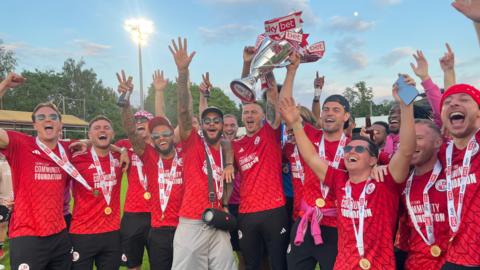 Crawley's players lifting the trophy