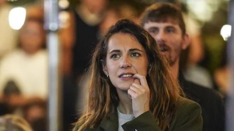 A woman bites her fingernail as she watches coverage of the US election