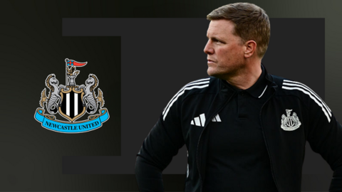 Eddie Howe with his hands on his hips and looking sideways, in front of a black background and the Newcastle club badge