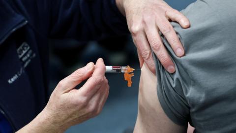 A vaccination is injected into a person's arm