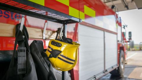 A stock image of a fireman's helmet hanging from the side of a fire engine.