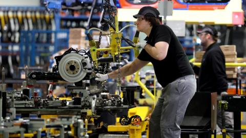 A worker uses a hoist to move components along the production line for the Qashqai model car at the Nissan car factory in Sunderland.
