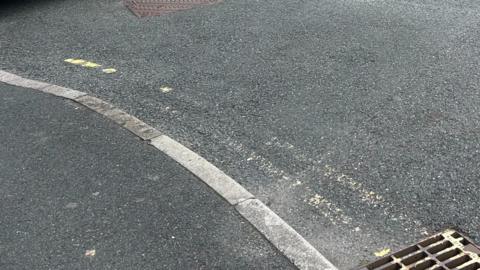 A close up of a faded set of parking yellow lines, beside a pavement.
