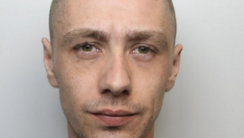 Ashley Darbyshire's police mugshot. He has a narrow face, a shaven head and stubble.