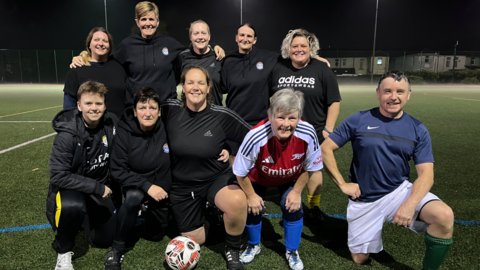 Caerphilly Castle walking football team pose for a group photo on the pitch, smiling at the camera