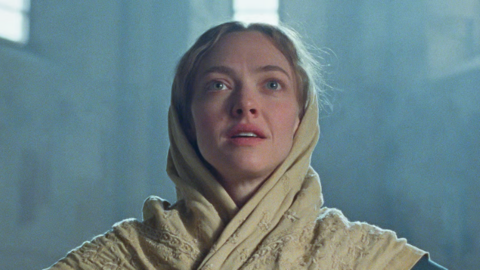 Amanda Seyfried playing Ann Lee in a scene from the film The Testament of Ann Lee. She has long blond hair tied and is wearing a beige shawl over her head and neck.