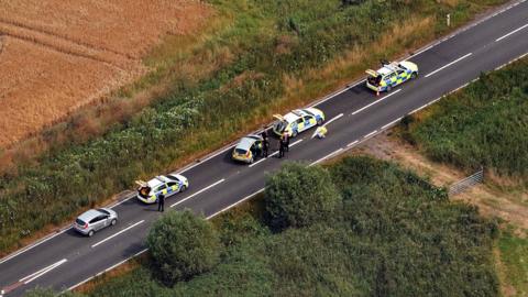 Five police vehicles at the scene of the collision on the Acle Straight