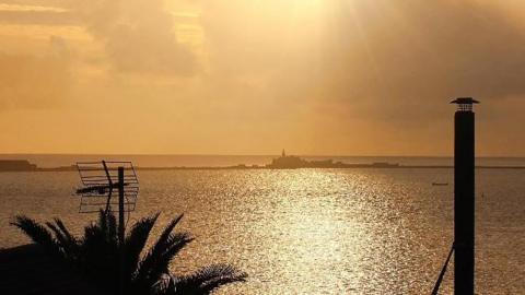 The sea at Weymouth illuminated in a yellowish orange by the low sun 