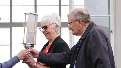 Frances Dodson and Peter Clare handing the torch of commemoration to an air cadet at Runnymede Air Forces Memorial