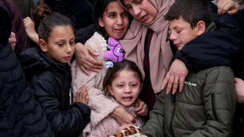 A woman has her arms around children, comforting them as they mourn the deaths of members of a Palestinian family in Tammoun, occupied West Bank.
