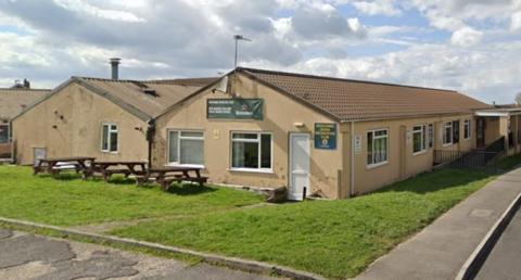 The recreation club, a one-storey building painted cream with pitched roof and picnic tables