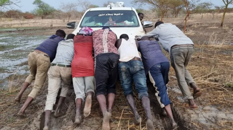 A group of men pushing a car