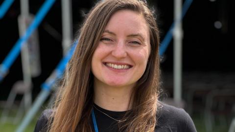 Hannah Wright has brown hair and is wearing a blue lanyard. She is smiling at the camera