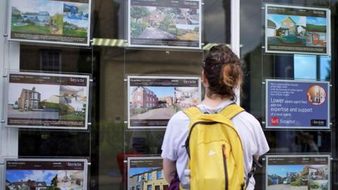 Woman looks in estate agent window 