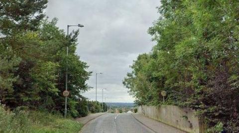 The Ballyeaston Road in Ballyclare. There are trees either side of a long stretch of road and a 30 MPH sign.