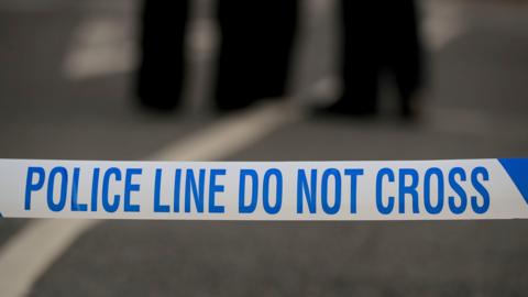 Blue and white police tape with a blurred background.