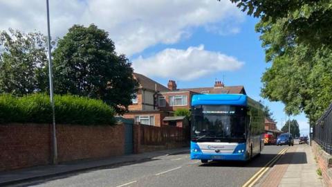 A Stagecoach North East bus travelling along a road. The vehicle has a light blue livery and dark windows.