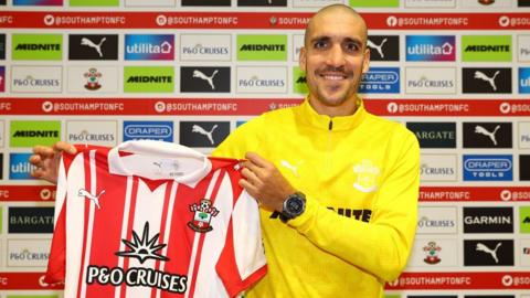 Oriol Romeu holding up a Southampton home shirt